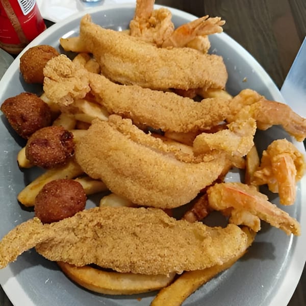 A plate of Southern Spice fried catfish, shrimp, french fries, and hush puppies.