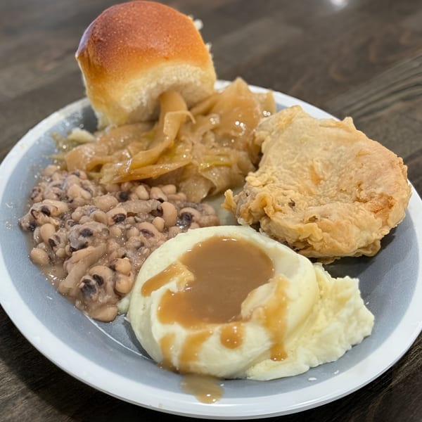 A Southern Spice meal with fried chicken, mashed potatoes and gravy, black-eyed peas, and a roll.