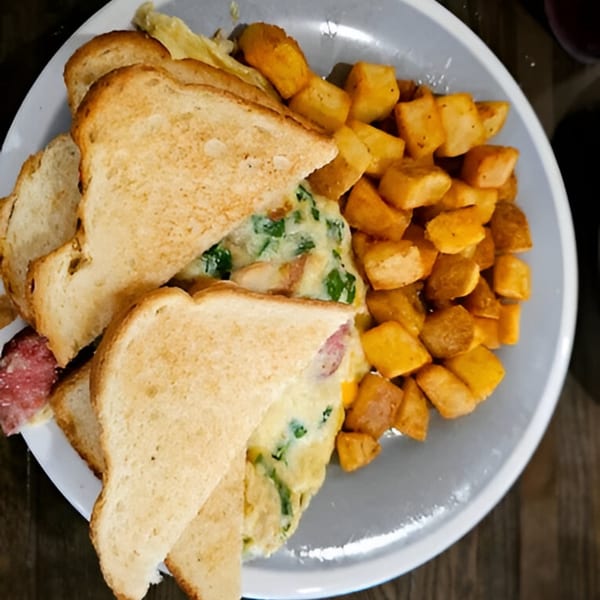 A Southern Spice breakfast plate with an omelet sandwich and a side of home fries.