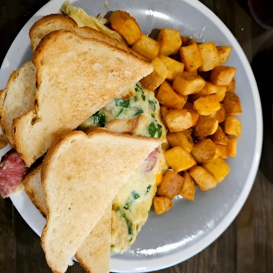 A Southern Spice breakfast plate with an omelet sandwich and a side of home fries.